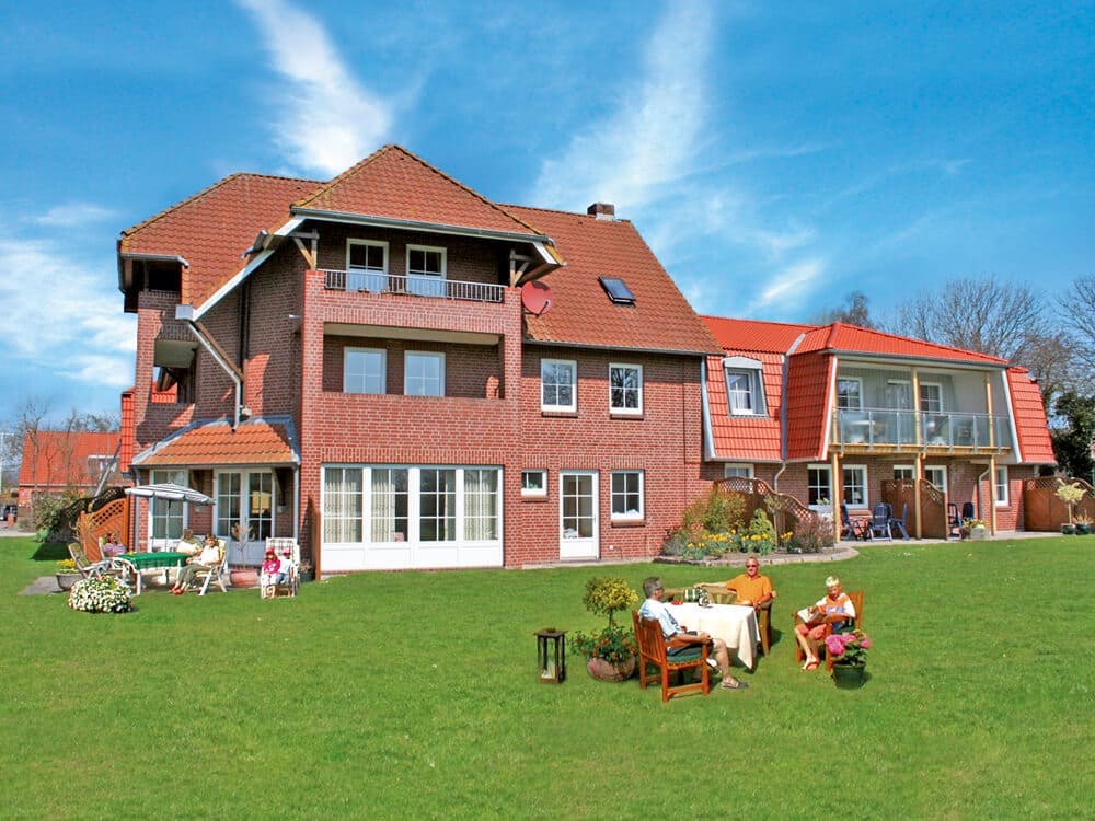 Außenansicht der Ferienanlage mit Gästen im Garten
